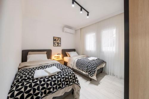 two beds in a room with white walls at Bodrum Center 2 Bedroom Calm Modern Garden Floor Flat - Yeni Dünya Bodrum in Bodrum City