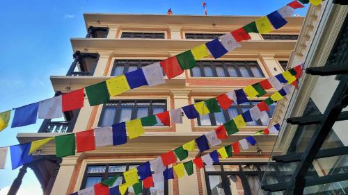 un bâtiment avec des drapeaux de prière colorés devant lui dans l'établissement SWARGA HERITAGE HOTEL - A TRADITIONAL STAY, à Katmandou
