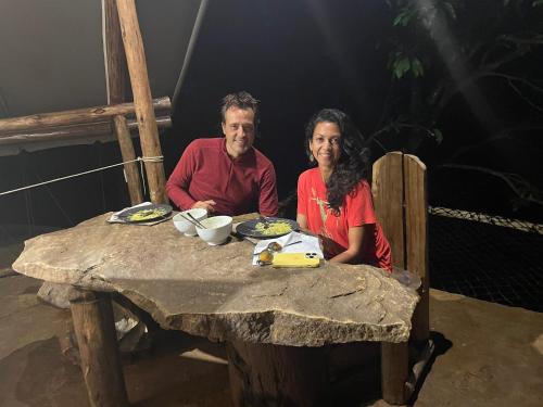 un hombre y una mujer sentados en una mesa en Ella Retreat Glamping Tent on Hill for Nature Lovers en Ella
