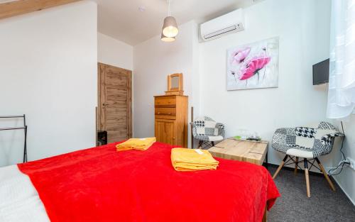 a bedroom with a red bed and a table and chairs at Penzion Alenka Valtice in Valtice