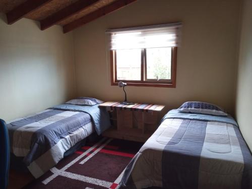 two beds in a room with a window at Hospedaje Martita Patagonia in Coihaique