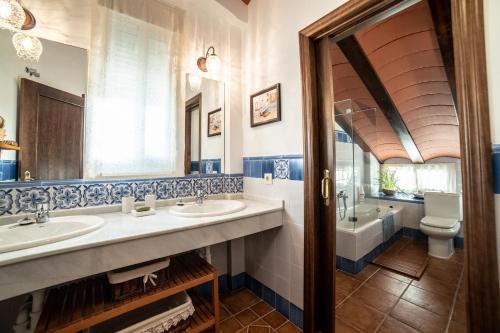 een badkamer met 2 wastafels, een bad en een toilet bij Casa el Refugio del Lago alojamiento rural in Córdoba