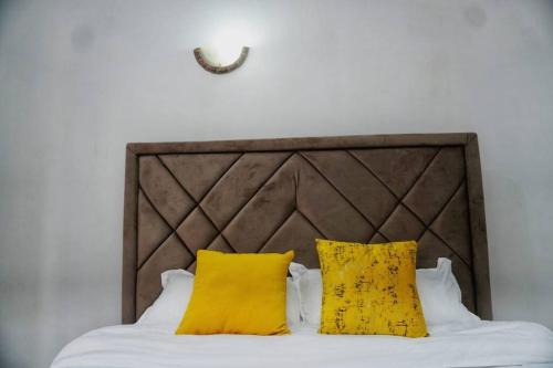 a bed with two yellow pillows on top of it at 3 bedroom furnished apartment at Kings Square in Eldoret