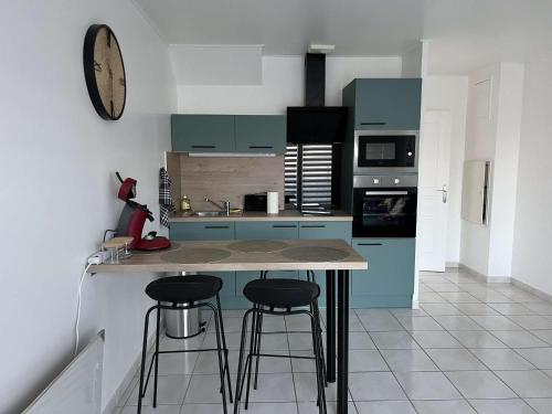 eine Küche mit blauen Schränken und 2 Barhockern in der Unterkunft Maison à Saint sauveur 10 minutes d'Honfleur in La Rivière-Saint-Sauveur