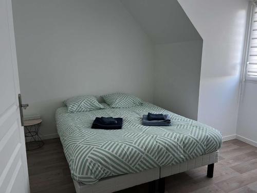 ein Bett in einem Zimmer mit zwei Handtüchern darauf in der Unterkunft Maison à Saint sauveur 10 minutes d'Honfleur in La Rivière-Saint-Sauveur