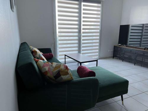 ein Wohnzimmer mit einem grünen Sofa und einem Tisch in der Unterkunft Maison à Saint sauveur 10 minutes d'Honfleur in La Rivière-Saint-Sauveur