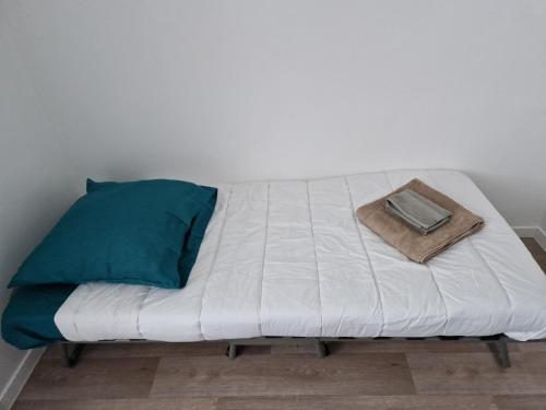 ein weißes Bett mit einem Kissen und einem Buch darauf in der Unterkunft Maison à Saint sauveur 10 minutes d'Honfleur in La Rivière-Saint-Sauveur