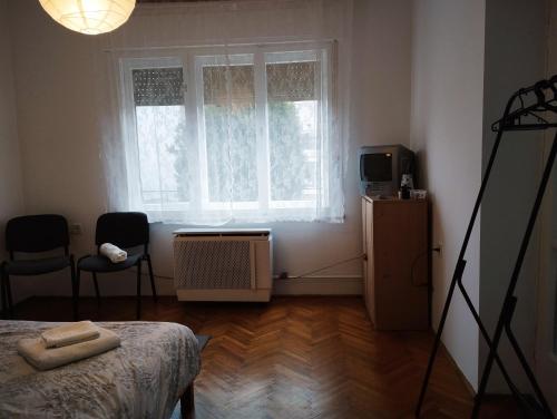 een slaapkamer met een bed, een televisie en een raam bij Róza Vendégház in Kiskunhalas