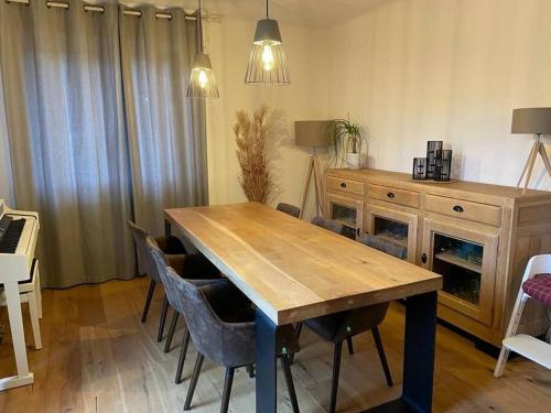 uma sala de jantar com uma mesa de madeira e cadeiras em Joli logement 6 à 8 pers avec terrasse La Cigale em Orbey