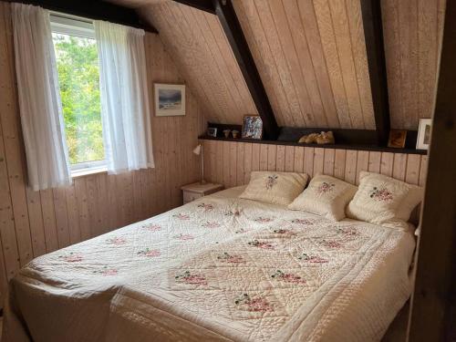 a bedroom with a large bed with a window at Charmerende sommerhus in Ringkøbing