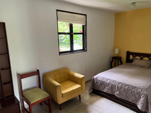 una camera da letto con un letto, una sedia e una finestra di Charming Nature House/ Finca Tradicional Cafetera ad Armenia