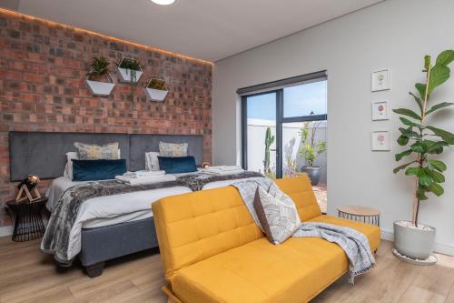 a bedroom with a bed and two yellow chairs at Lemon Tree Studio 991 in Langebaan