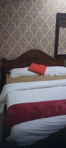 a bedroom with a bed with a red pillow on it at S R HOTEL & RESTAURANT in Lucknow