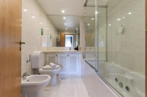 a bathroom with a toilet and a tub and a sink at Telheiras Premium by Homing in Lisbon