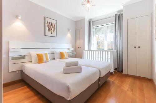 a bedroom with a large white bed with yellow pillows at Telheiras Premium by Homing in Lisbon
