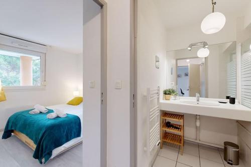 a white bedroom with a bed and a sink at My Cozy Flat - Côté Jardin - Parking - Terrasse in Toulouse