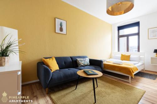ein Wohnzimmer mit einem blauen Sofa und einem Bett in der Unterkunft Pineapple Apartments Dresden Zwinger in Dresden