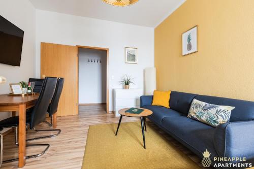 een woonkamer met een blauwe bank en een tafel bij Pineapple Apartments Dresden Zwinger in Dresden