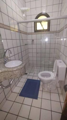a white bathroom with a toilet and a sink at Casa para temporada em Anagé 