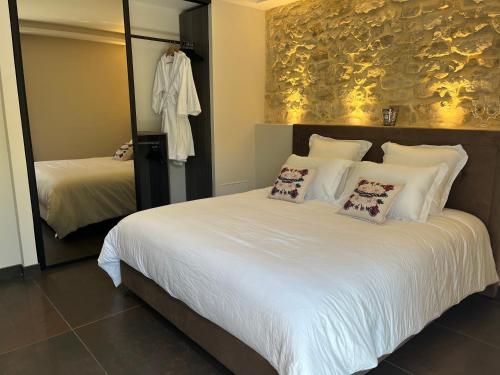 a bedroom with a large white bed and a mirror at Domaine de La Franquette by Bridget & Pascal - Piscine Chauffée & SPA in Caderousse