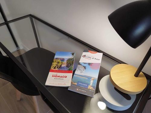 two books on a table with a lamp and a chair at Appartement moderne refait à neuf - 4 couchages - MENTON in Menton
