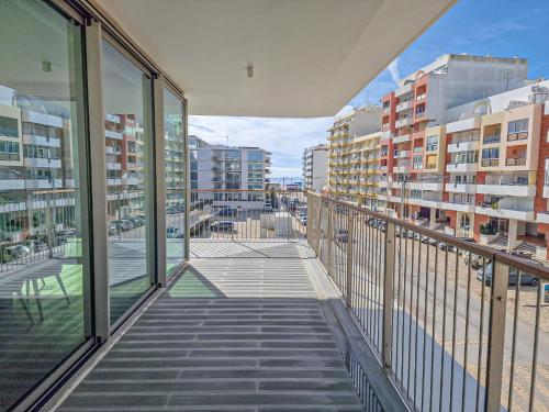 balcón con puertas de cristal y vistas a la ciudad en Bayline Condominium - Heated indoor Swimming pool - SPA - By Bedzy, en Armação de Pêra