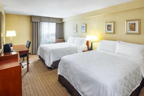 a hotel room with two beds and a desk at Holiday Inn Laval Montreal, an IHG Hotel in Laval