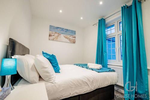 a bedroom with a bed with blue curtains and a window at Guest Homes - Broadland House in Southampton