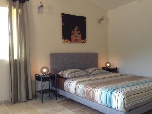 1 dormitorio con 1 cama y una pintura en la pared en La Grande Bouisse, en Céreste