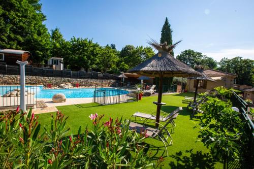 un patio trasero con piscina y césped con sombrilla en Camping Les Cruses, en Ribes