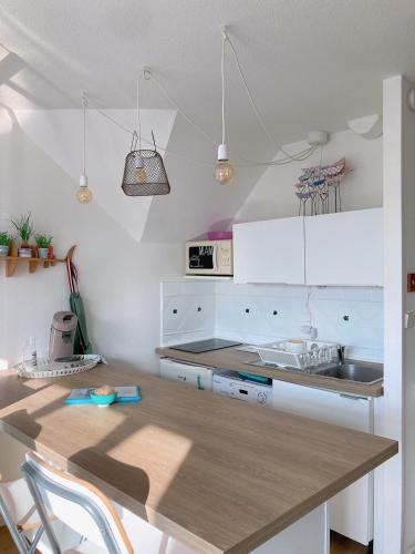 une cuisine avec des armoires blanches et une table en bois dans l'établissement Le Bulot Bleu *Terrasse couverte *Parking *2 vélos, à Carnac