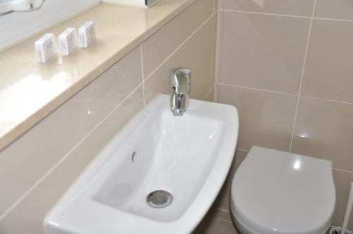 a bathroom with a white sink and a toilet at Queens Hotel in London