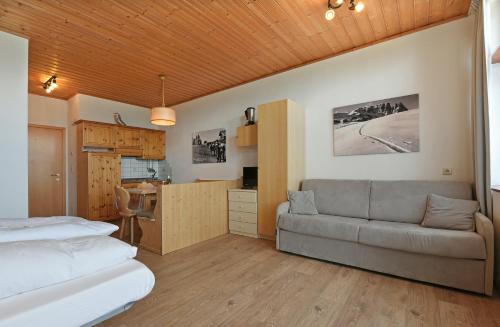 a bedroom with a bed and a couch and a kitchen at Appartaments Alpi in Seiser Alm 