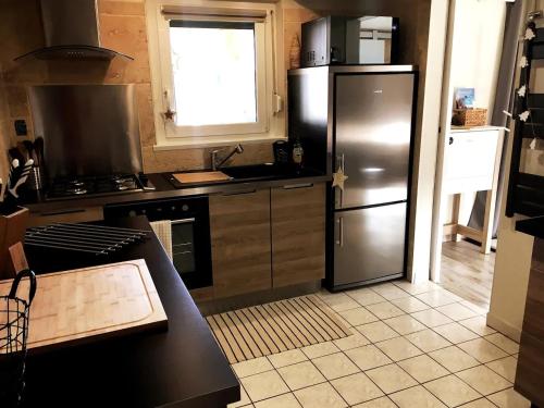 Il comprend une cuisine équipée d'un réfrigérateur en acier inoxydable et une fenêtre. dans l'établissement Joli Appartement Cosy 2 à 4 pers avec terrasse La Fourmi, à Orbey