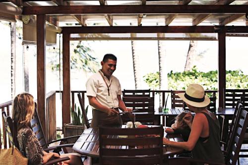 un homme debout sur une terrasse couverte avec des personnes assises à une table dans l'établissement Las Flores Resort, à Chirilagua