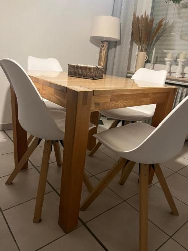 einem Holztisch mit zwei weißen Stühlen und einem Tisch mit einer Lampe in der Unterkunft Strandstern Norddeich in Norddeich