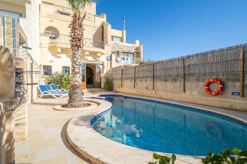 una piscina con una palmera al lado de un edificio en 3 Bedroom Holiday Home with Large Private Pool and Views, en Xewkija