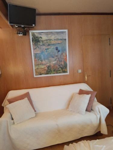 un canapé blanc assis dans un salon avec une télévision dans l'établissement Arc de triomphe studio charme authentique, à Paris