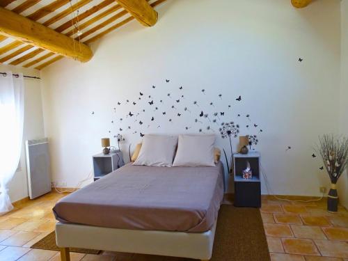 sypialnia z łóżkiem z czarnymi motylami na ścianie w obiekcie Logement charme provençal w mieście Cabannes