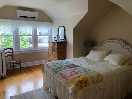 a bedroom with a bed and a dresser and windows at Knight Campbell Carriage House in Denver