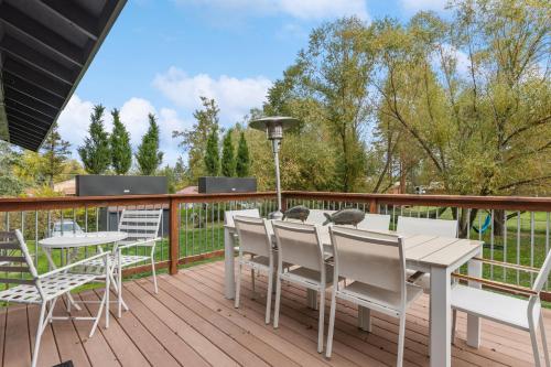 a deck with a white table and chairs at Open Sky Retreat - Close to Trails, Private Hot Tub, Big Yard, & Kid Friendly in Whitefish