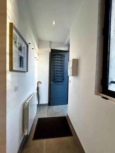 un pasillo con una puerta azul y una alfombra en Maisonnette 2 pers tout confort près de Paris en Bobigny