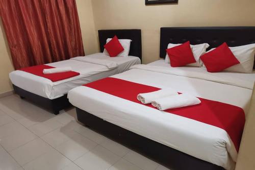 two beds in a hotel room with red and white pillows at Langkawi Tok Jah Guest House Pantai Cenang in Pantai Cenang