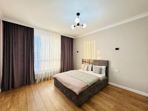 a bedroom with a bed and a large window at Nexpo City 2-Room Apartments in Astana