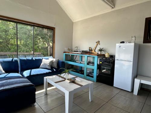 a living room with a blue couch and a white refrigerator at Blue Lagoon Cottage in Umngazana