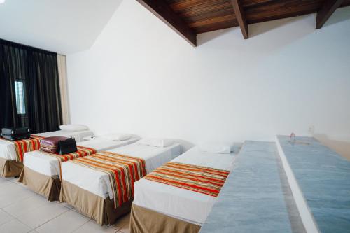 a row of beds in a room with a pool at Hotel VillaOeste in Mossoró