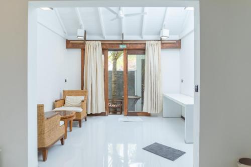 a living room with a couch and chairs and a window at Brickwood Ganduvaru Private Villas in Rasdu