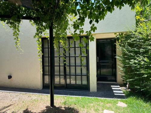 un edificio con una puerta negra y un árbol en ArquiArts Casa-Departamento en Barrio Huerto del Sol en 