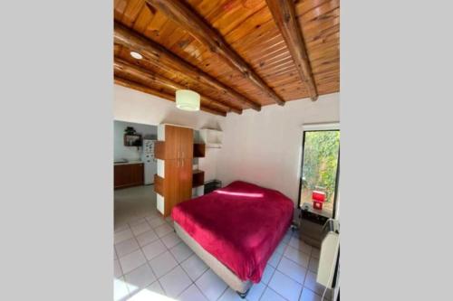 1 dormitorio con 1 cama con manta roja en ArquiArts Casa-Departamento en Barrio Huerto del Sol en 