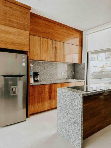 a kitchen with a stainless steel refrigerator and wooden cabinets at Casa Calec 2BR Apartment with Pool & Terrace in Manzanillo